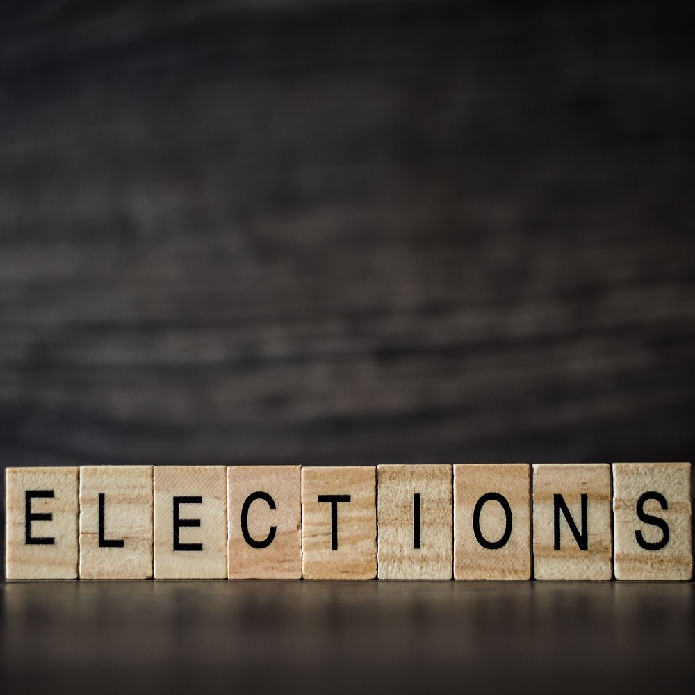 the word elections, consisting of light wooden square panels on a dark wooden background